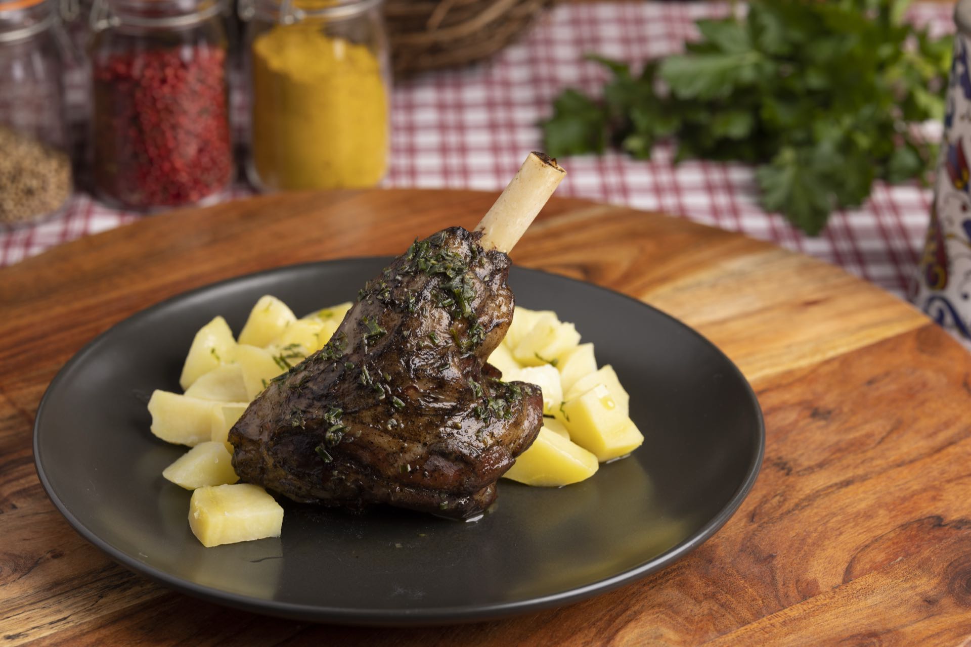 Geschmorte Lammhaxe mit Kartoffeln auf schwarzem Teller