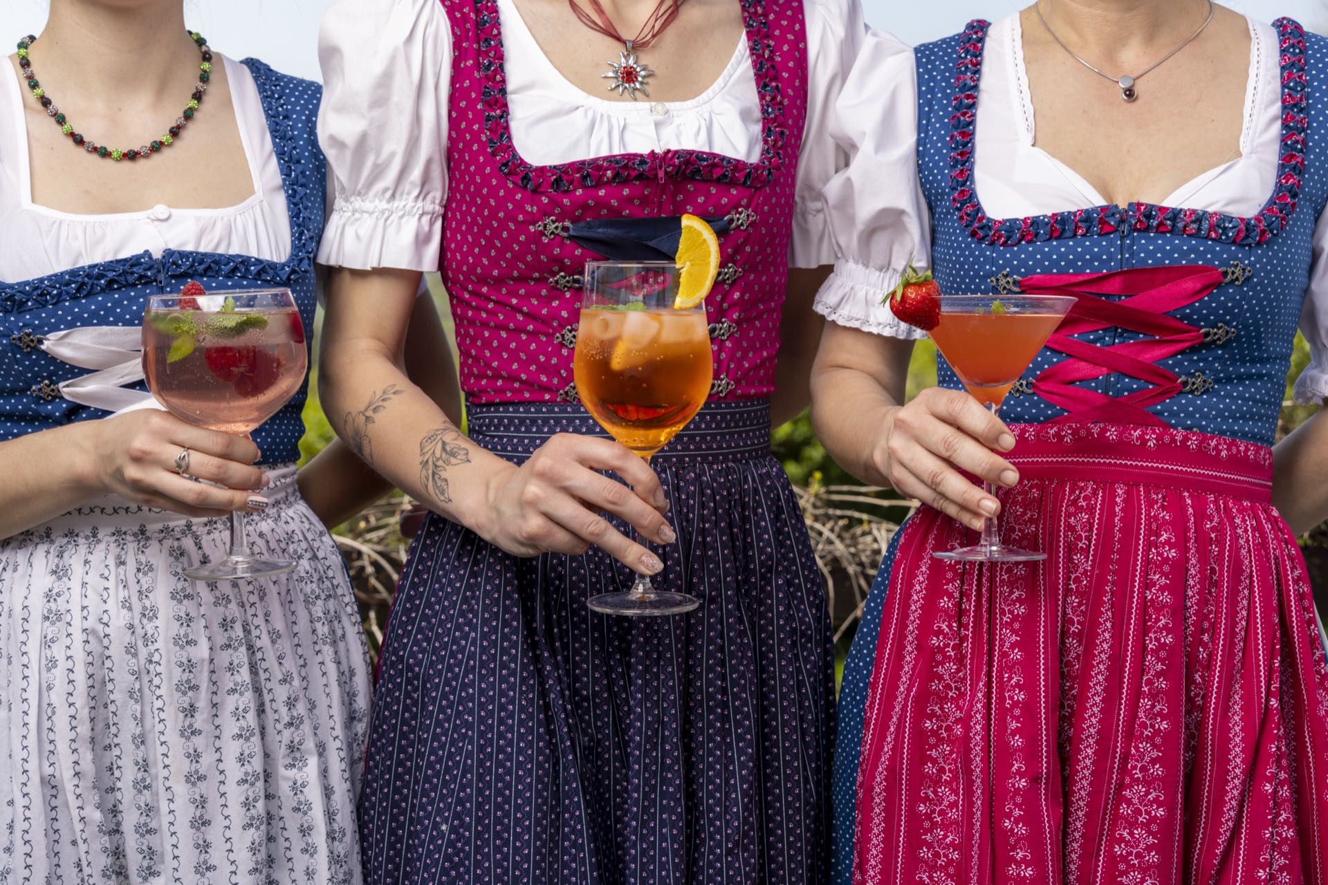 Drei Kellnerinnen im Dirndl mit bunten Cocktails